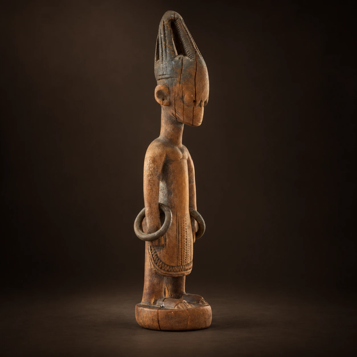 Vista de perfil de una figura Ibeji yoruba sobre fondo oscuro